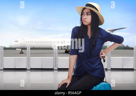 Ritratto di viaggiatori asiatici donna con la faccia triste seduto sulla valigia Foto Stock
