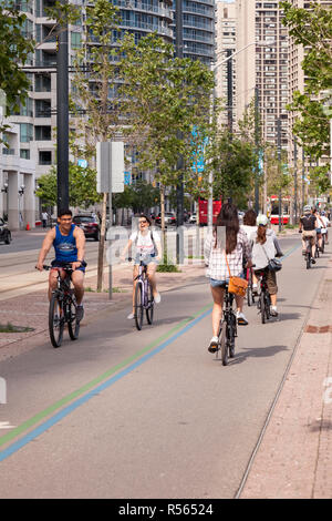 I ciclisti utilizzando una pista ciclabile su Martin Goodman Trail che segue la Toronto waterfront su Queens Quay. Città di Toronto, Ontario, Canada. Foto Stock