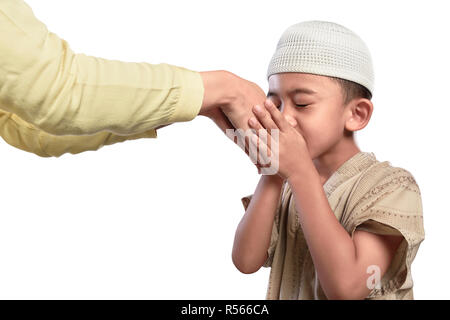 Poco musulmani asiatici capretto nel tappo bianco baciare la mano dei genitori Foto Stock