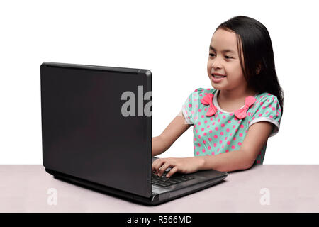 Allegro asian bambina utilizzando laptop sulla scrivania Foto Stock