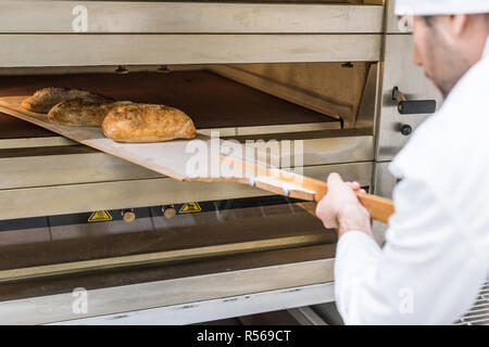 Il panettiere maschio di prendere il pane appena sfornato Foto Stock