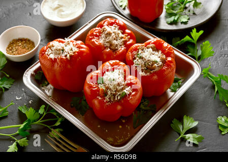 Farcite i peperoni rossi con carne macinata, riso, cipolla, formaggio parmigiano sulla pietra nera tabella. Foto Stock