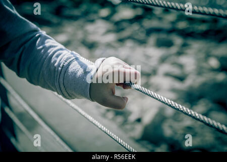 Giovane ragazzo in mano che trattiene il filo metallico recinzione Foto Stock