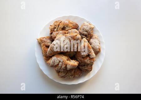 Croissant appena sfornati sulla piastra isolata su sfondo bianco da un elevato angolo di visione Foto Stock