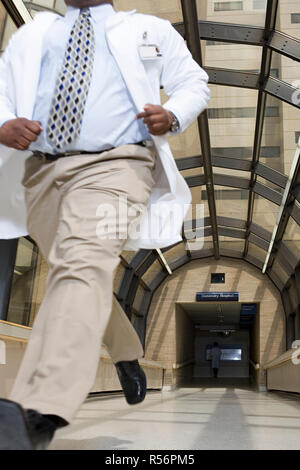 Dottore in esecuzione attraverso ospedale Foto Stock