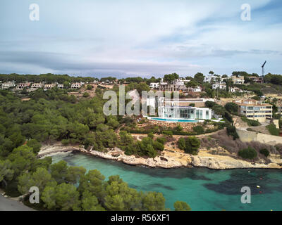 Ricche ville sulla Cala del Mago litorale con verde chiaro trasparente di acqua di mare, le nuvole. Mallorca o Maiorca, isole Baleari, Spagna Foto Stock