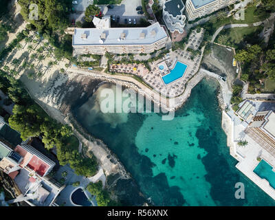 Mallorca, Spagna - 5 Novembre 2018: gli appartamenti di lusso e hotel con piscina e sedie a sdraio sulla costa di Cala Vinyes, verde trasparente wate Foto Stock