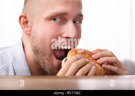Ritratto di un avido giovane mangiare hamburger Foto Stock