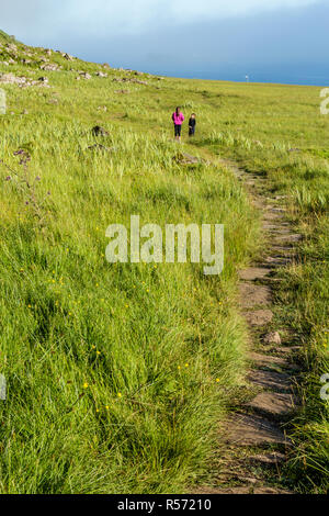Ragazzo e una ragazza e permanente in chat alla fine di un sentiero roccioso, Garrafad, Isola di Skye, Ebridi Interne, Scotland, Regno Unito Foto Stock