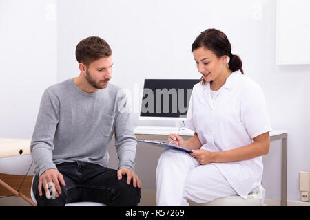 Giovani donne medico con appunti dando la prescrizione al paziente di sesso maschile Foto Stock