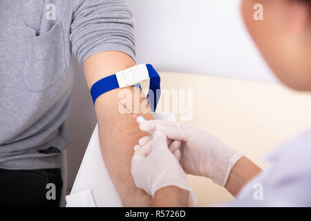 Close-up di medico siringa di iniezione nel braccio del paziente per raccogliere il campione di sangue Foto Stock
