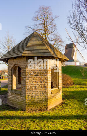 Belgio, Bruges, Bonne Chiere, una chiusura di un verde lussureggiante campo con il percorso che conduce al mulino a vento tramonto Foto Stock