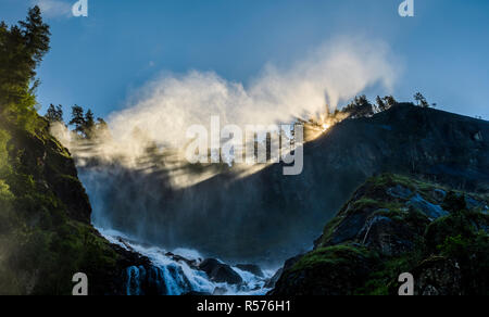 La luce del sole che splende attraverso gli alberi nella parte superiore della cascata Latefossen vicino a Odda, Norvegia in estate. Foto Stock