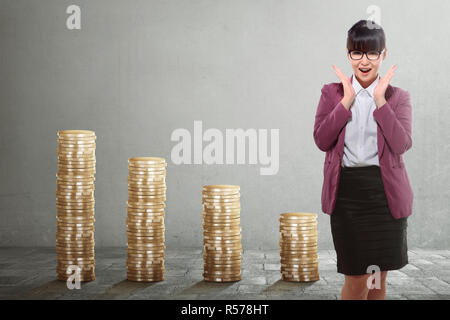 Bella asian business woman standing con pila dorato delle monete in euro Foto Stock