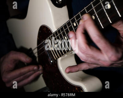 Inquadratura ravvicinata di un chitarrista giocando su una chitarra elettrica, con motion blur delle mani Foto Stock