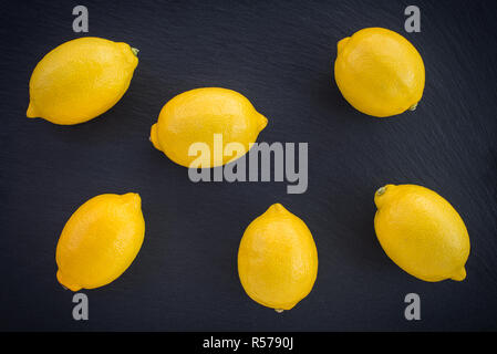 Limoni freschi su ardesia scuro dello sfondo. Mature di agrumi. Foto Stock