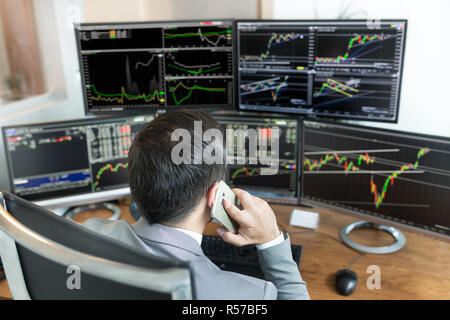 Oltre la spalla di stock broker trading online, parlando al telefono cellulare. Foto Stock