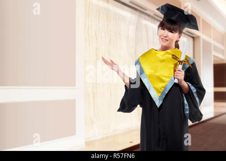 Bella donna asiatica con cappuccio di graduazione e certificato di contenimento Foto Stock