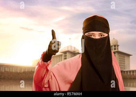 Bella asiatica donna musulmana con niqab che mostra i pollici Foto Stock