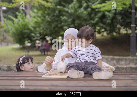 Ritratto di bella giovane madre che insegna ai suoi figli risparmiare denaro per un futuro migliore. Foto Stock