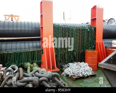 Le catene e i ganci sul ponte della nave pipelaying. Rack con tubazioni Foto Stock