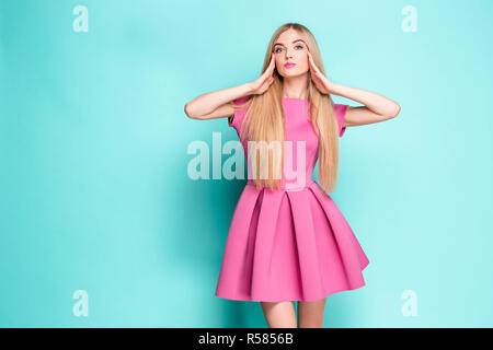Sorridente bella giovane donna in rosa mini abito in posa in studio Foto Stock