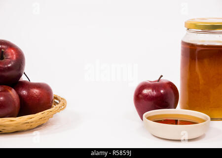 Pila di mele e red apple e un vasetto di miele ciotola di miele isolato su uno sfondo bianco Foto Stock