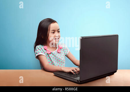 Sorridente bambino asiatico con computer portatile sul tavolo Foto Stock