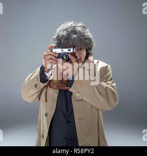 L'uomo anziano come detective o boss della mafia su grigio di sfondo per studio Foto Stock