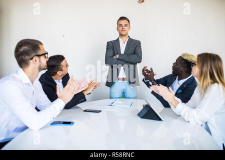Maschio di indirizzamento Boss riuniti attorno al tavolo della sala riunioni Foto Stock