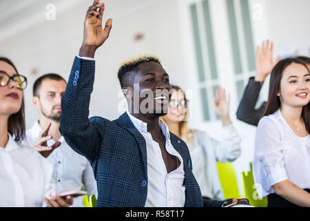 Ho una domanda. Gruppo di persone sedute a sdraio nella sala conferenze, alzando le mani. Business e imprenditorialità evento. Foto Stock