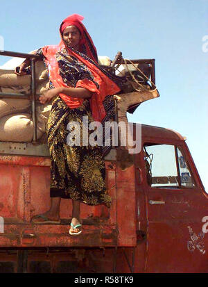 1993 - dritto sulla ripresa di una donna somala aggrappandosi al lato destro del rack dump su un motore Isuzu autocarro con cassone ribaltabile. Lei guarda gli uomini caricamento dei sacchi di grano donati dal popolo dell Australia (non mostrato). Questa missione è a diretto sostegno di Restore Hope. Foto Stock