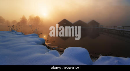 Sunrise in inverno sulle capanne pescatore al lago, Kochelsee, dello Stato libero di Baviera, Germania Foto Stock