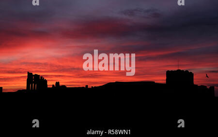 Il sole sorge sulle rovine del Priorato di Tynemouth in North Shields. Foto Stock