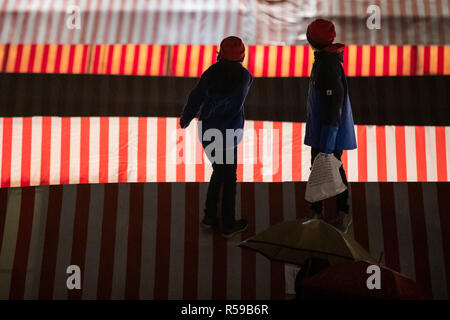 La Baviera, Germania. 30 Nov 2018. Due ragazzi sono in piedi sul tetto di un mercato in stallo durante l'apertura ufficiale della fiera di Norimberga Mercatino di Natale 2018. Migliaia di visitatori hanno sfidato la pioggia e la sera presto ascoltato il prologo del Cristo Bambino nella galleria della Frauenkirche. Foto: Daniel Karmann/dpa Credito: dpa picture alliance/Alamy Live News Foto Stock