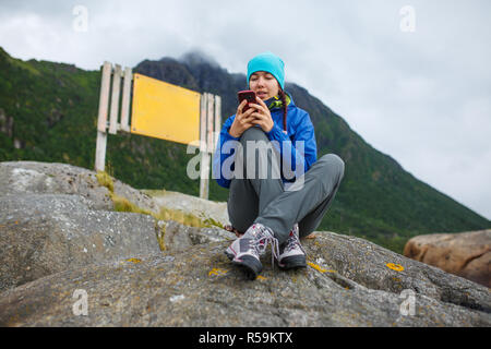 Foto di donna con il telefono in mano seduto sulla collina sullo sfondo della compressa vuota Foto Stock