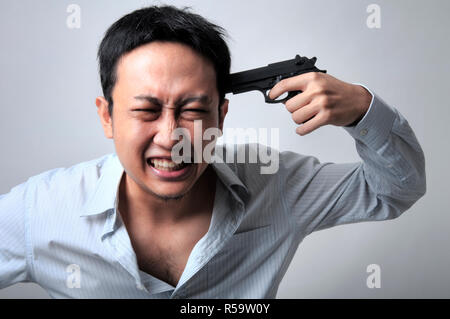 Imprenditore asiatico che punta una pistola sulla sua testa Foto Stock