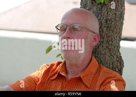 Senior prende un pisolino sotto agli alberi Foto Stock