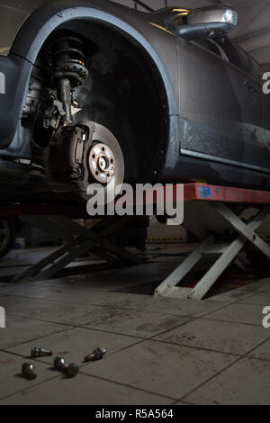 All'interno di un garage - moderna auto in attesa per il meccanico per cambiare le sue ruote/pneumatici (SHALLOW DOF dai toni di colore immagine) Foto Stock