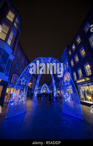 Londra - Novembre 23, 2018: Venerdì nero gli amanti dello shopping a piedi sotto gli archi di Natale Decorare South Molton Street, un elegante pedonale distretto di vendita al dettaglio. Foto Stock