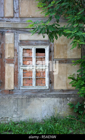 Finestra di un inutilizzato, decadeva casa in legno e muratura Foto Stock