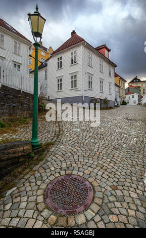 La vecchia strada storica in districk di Bergen. Ripida marciapiede, lampada e tombino in uno scenario di autunno Foto Stock