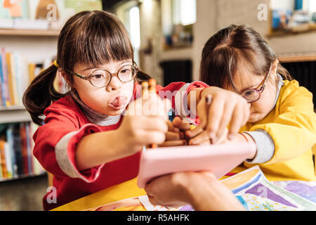 Sunny bambino. Dark-eyed bella carino sunny bambino che gioca con la sua groupmate in kindergarten Foto Stock