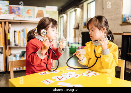 Far finta di essere medico. Due graziosi soleggiata piacevole bambini fingendo di essere i medici a giocare in una scuola materna Foto Stock