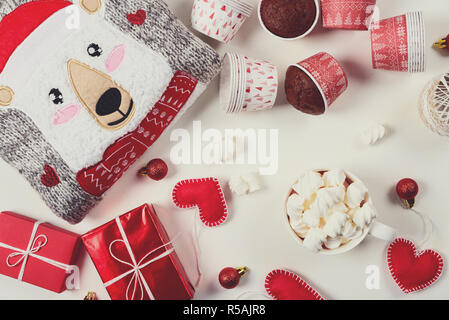 I regali di Natale. Felpa lavorata a maglia, pantofole, confezioni regalo, muffin al cioccolato e la cioccolata calda con marshmallow prevista su di un legno bianco backgroun tabella Foto Stock