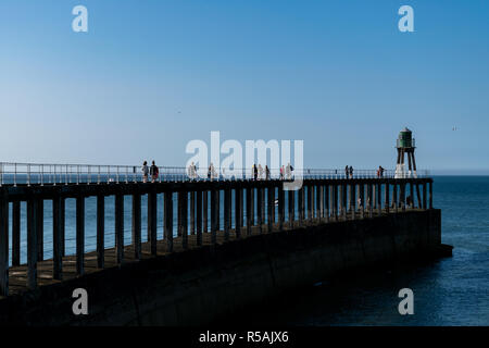 Persone in piedi lungo la Whitby Molo Ovest di estensione Foto Stock