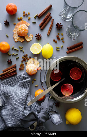 Vin brulé in casseruola in alluminio grigio su un tavolo di legno. Natale o per il riscaldamento invernale drink. Ingredienti: vino, limone, bastoncini di cannella, anice, cardamomo, Foto Stock