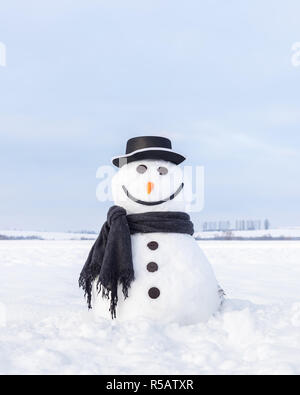 Divertente pupazzo di neve in elegante cappello e scalf nero sul campo nevoso. Buon Natale e felice Anno Nuovo! Foto Stock