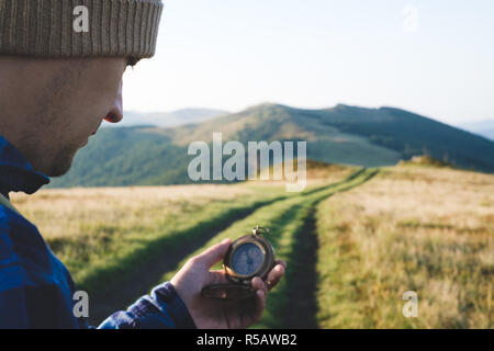 L'uomo con la bussola in mano sulla strada delle montagne. Concetto di viaggio. Fotografia di paesaggi Foto Stock