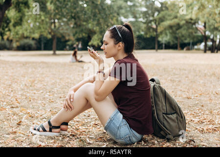 Giovane bella ragazza parla di un comando vocale in un telefono cellulare. La persona che utilizza un gadget moderno. Foto Stock